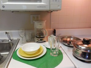 A kitchen with a GE microwave, a coffee maker, and stainless steel cookware on the counter. - Affordable Suites Shelby (Shelby)