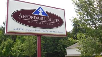 Schild für Affordable Suites of America, mit einem Kastanienbraun- und Weißfarbton und einem blauen Logo.