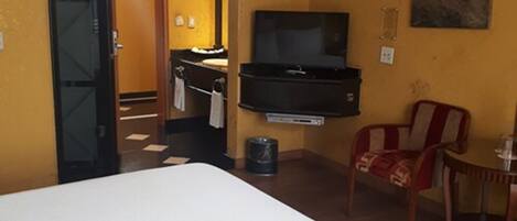 A hotel room with a bed, a television, a chair, and a small table.