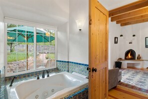 Ein Badezimmer mit einer großen Badewanne, einem Fenster mit Blick ins Freie und einem Kamin.