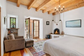 Ein Schlafzimmer mit einem großen Bett, einem Kamin, einer Couch und einer Leseecke mit Büchern und einer Lampe.
