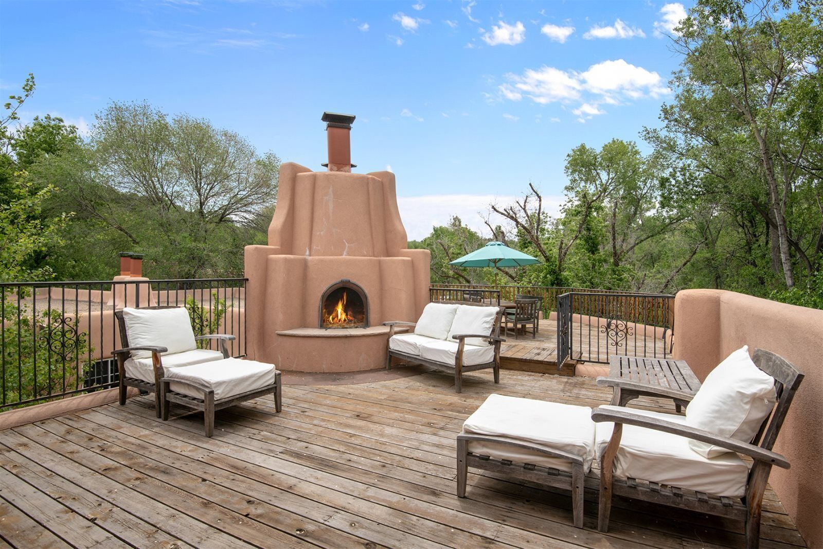 An outdoor patio with a stone fireplace, wooden deck, and outdoor furniture.
