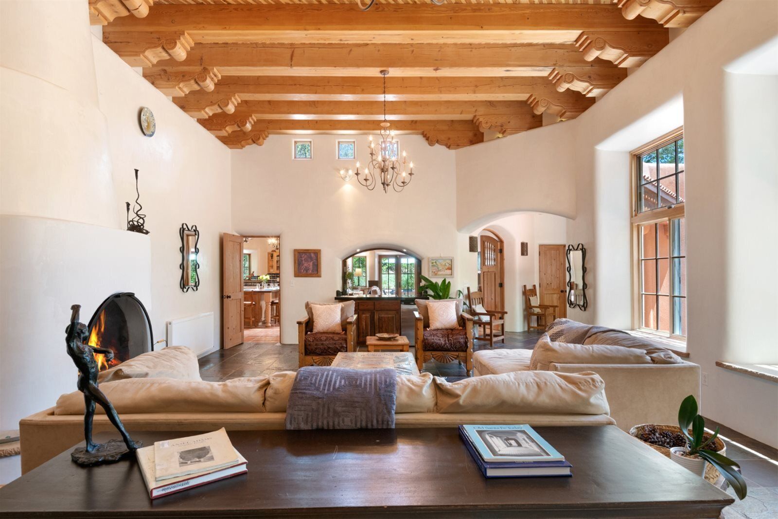 Uma sala de estar ampla com lareira, móveis de madeira e vista para a cozinha.