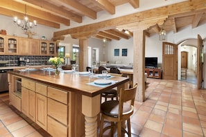 A spacious kitchen with a large island, wooden cabinets, and a tiled floor.