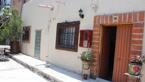 A building with a brick entrance, a window with metal bars, and a potted plant outside. - Casa de Huespedes Independencia (San Miguel de Allende)