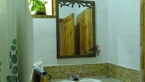A bathroom with a white sink, a mirror, and a window with a plant. - Ecofinca Luna del Puente (Santa Cruz de Yojoa)
