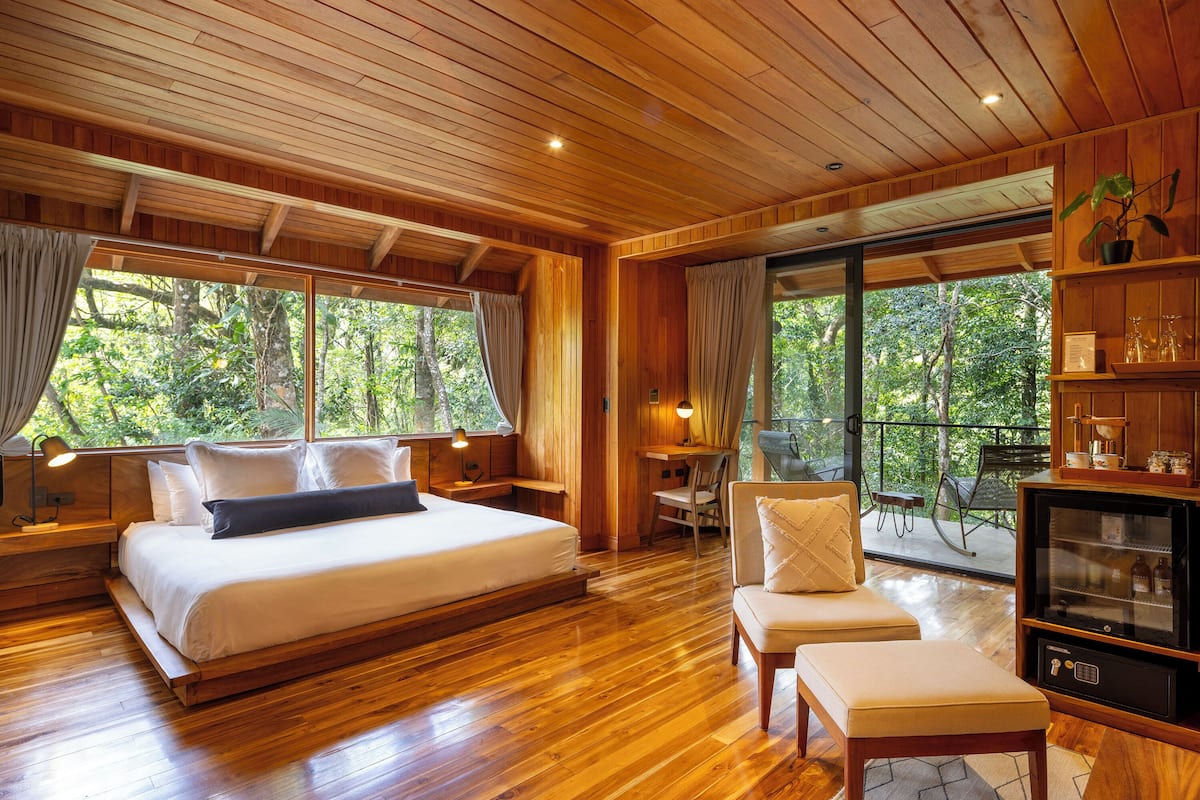 Une chambre avec un plancher en bois, un grand lit, un coin salon et un téléviseur.