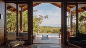 Un intérieur moderne avec une grande porte vitrée donnant sur un espace extérieur doté d’une piscine et entouré de verdure.