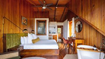 A wooden interior with a bed, desk, and bathtub.