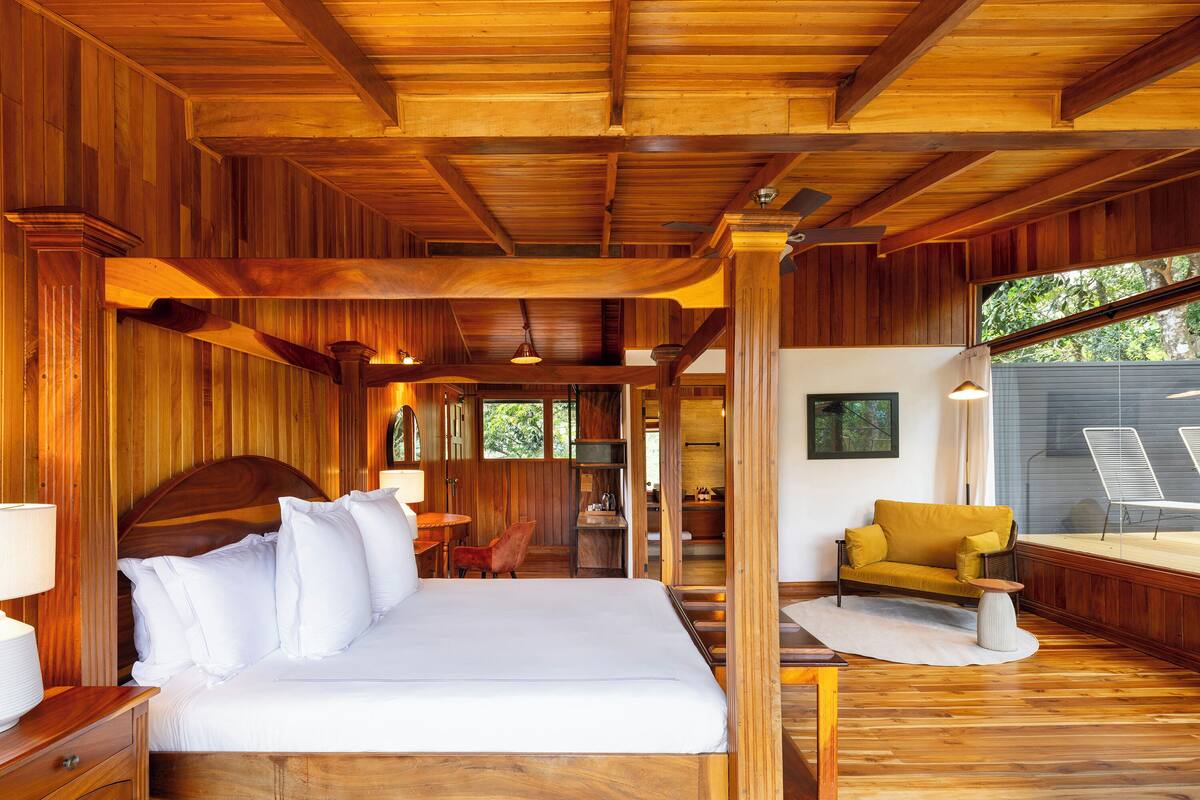 Une chambre aux murs lambrissés, avec un lit, un canapé et une petite table.