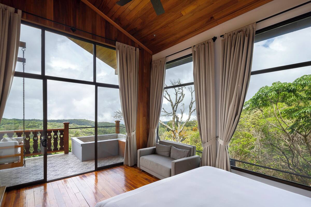 Une pièce spacieuse avec de grandes fenêtres, un plafond en bois et un balcon offrant une vue sur le paysage.