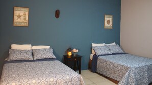 A bedroom with two beds, a nightstand with a lantern, and two wall decorations. - Private Front Beach House (Huehuete)