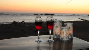 A table with two wine glasses and three candle holders on a beach at sunset. - Private Front Beach House (Huehuete)
