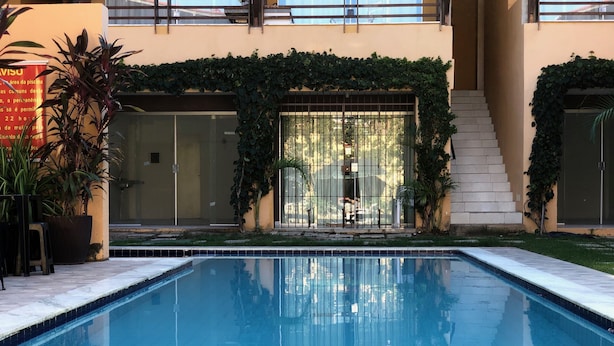 En swimmingpool med en glasdør indgang, omgivet af plantekasser og en trappe der fører op til en etage.