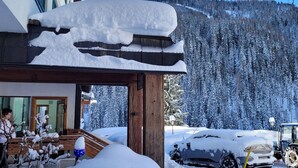 A building with a snow-covered roof and a view of a forested mountain. - Hotel Nockalm (Krems in Kaernten)
