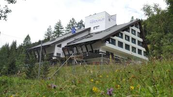 Situated in a lush environment, the Hotel Nockalm features a distinctive sloped roof design and a prominent signboard.