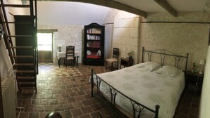 Ein Schlafzimmer mit einem Bett, einem Holzstuhl, einem Bücherregal und einer Treppe.