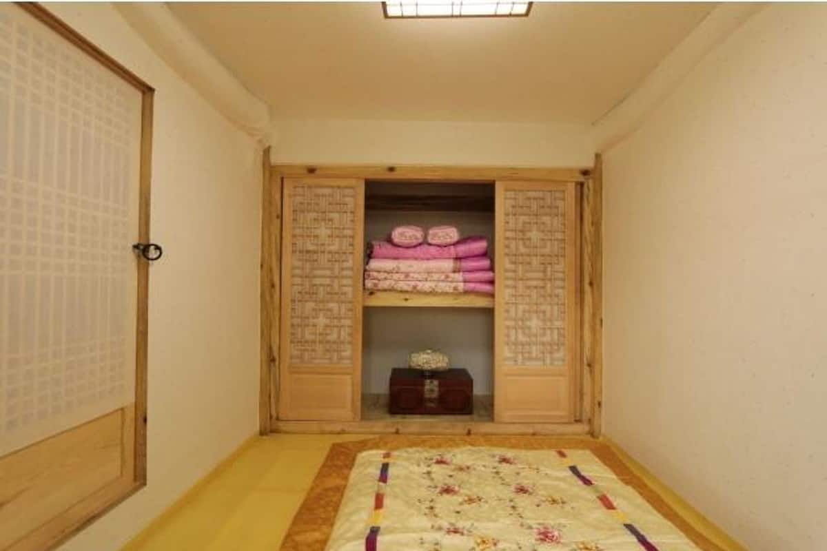 A traditional Japanese room with tatami flooring, a low wooden bed, and a sliding door with calligraphy.