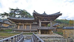 A traditional wooden building with a tiled roof, a stone wall, and a wooden bridge in the foreground. - Gwiae Traditional House (Yeongcheon)
