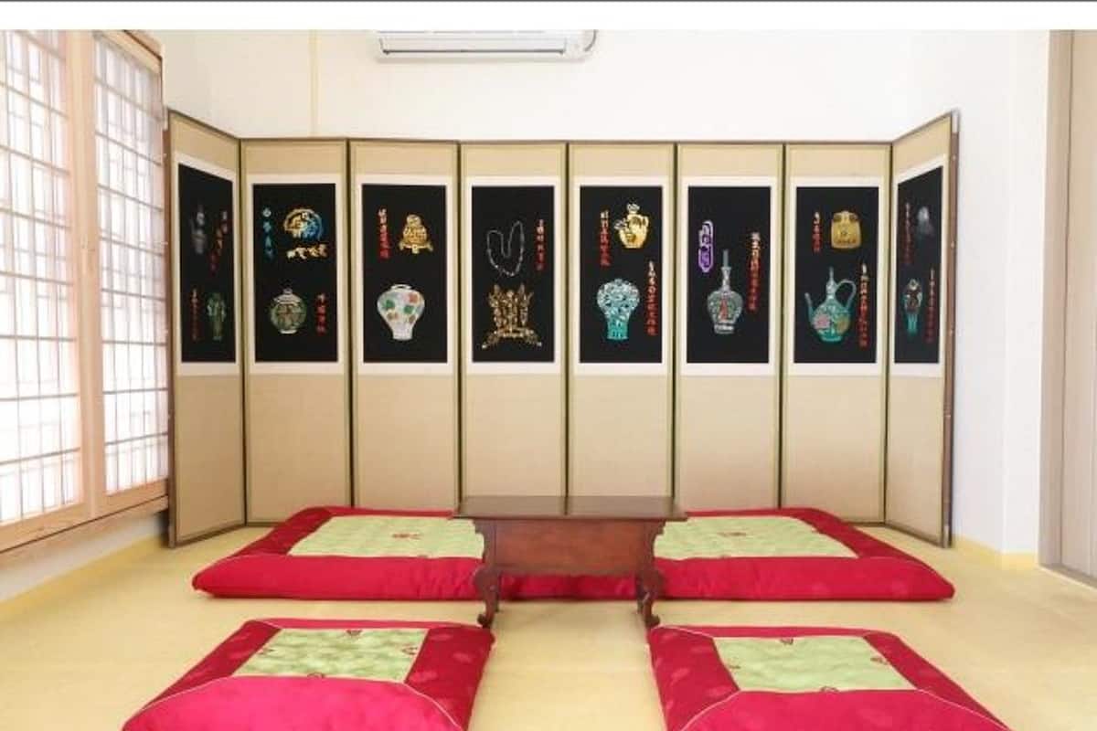 A room with a tatami mat floor, a low wooden table, and a shoji screen with framed artwork.