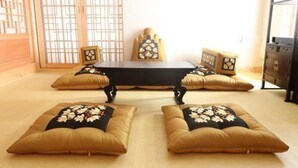 A room with a central table, four matching cushions, and a traditional sliding door. - Gwiae Traditional House (Yeongcheon)