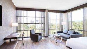 Une chambre d’hôtel moderne, dotée d’un grand lit, d’un canapé, d’un bureau avec une chaise et d’une petite table.