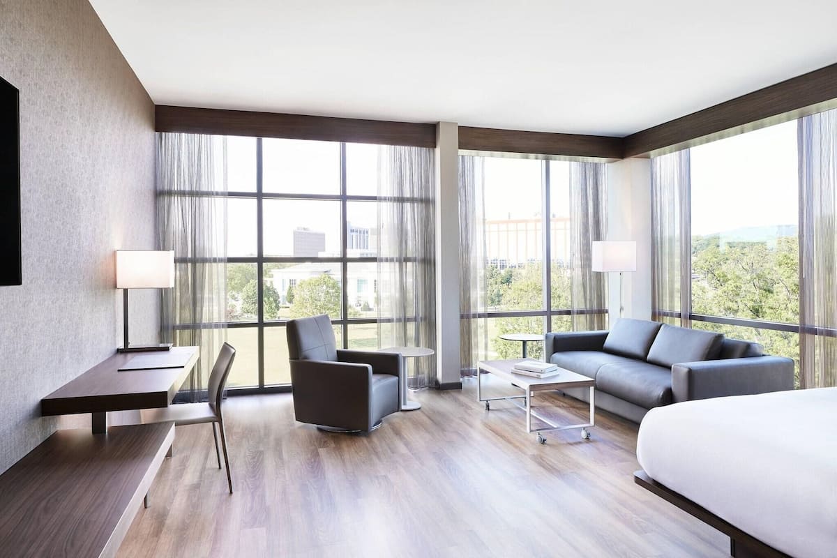 Une chambre d’hôtel moderne, dotée d’un grand lit, d’un canapé, d’un bureau avec une chaise et d’une petite table.