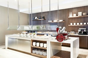 A modern breakfast bar with a coffee machine, a fruit display, and a variety of breakfast items. - AC Hotel Huntsville Downtown (Huntsville)