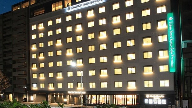 A hotel with a row of uniformly lit windows, a sign indicating it is an Urban Hotel Kyoto-Gojo Premium, and a green sign on the right side. - Urban Hotel Kyoto Gojo Premium (Kyoto)