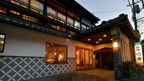 A traditional Japanese building with a tiled entrance, a wooden porch, and a sign with Japanese characters. - Takezono Ryokan (Shimonoseki)