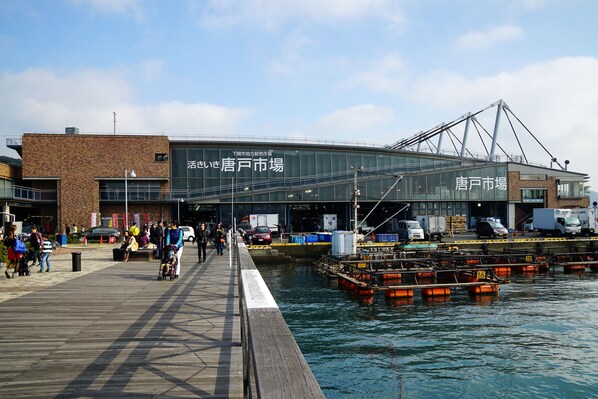 A waterfront building with a large glass facade, a dock with boats, and a pedestrian walkway. - Takezono Ryokan (Shimonoseki)