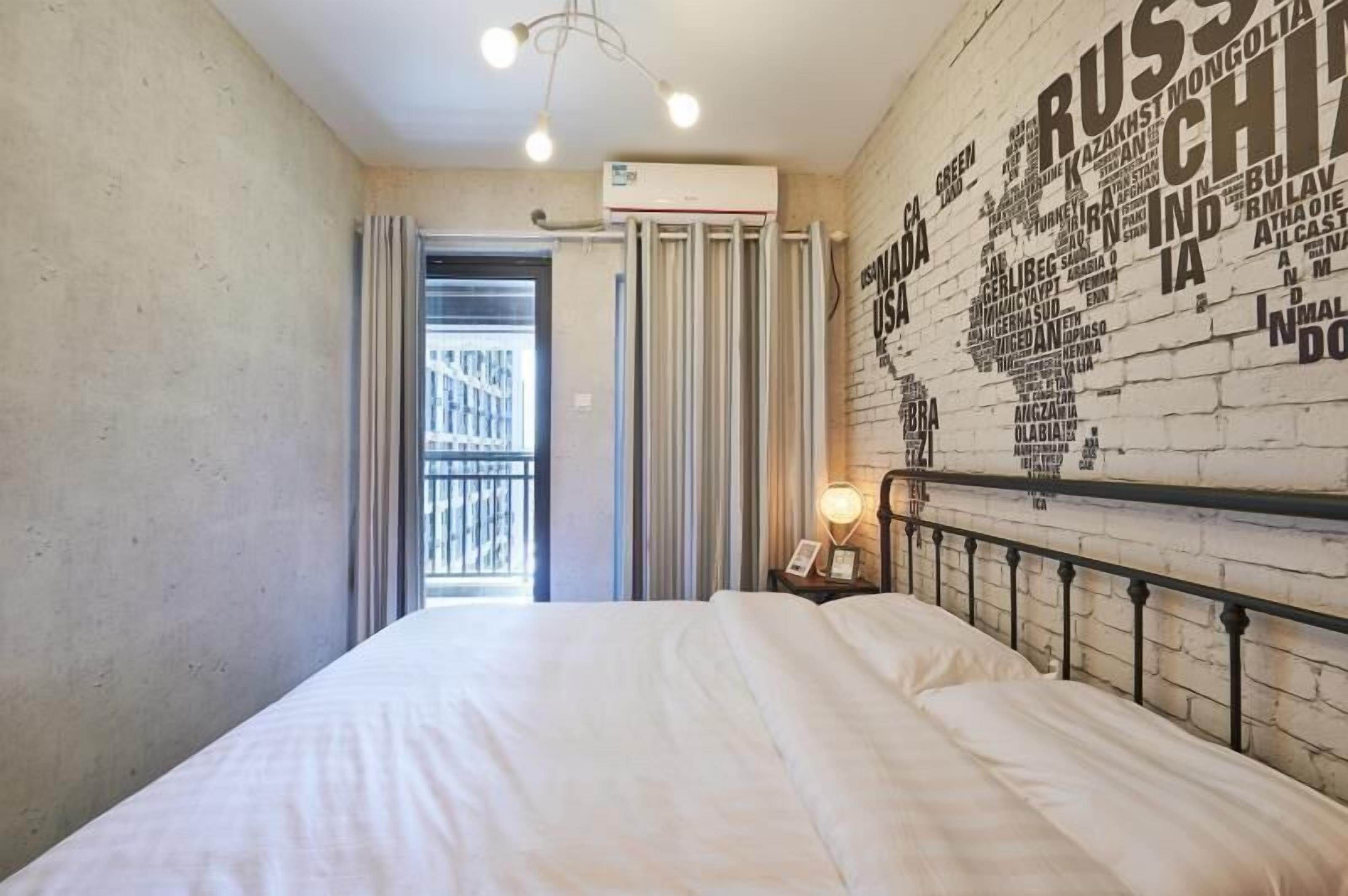 A hotel room with a large bed, a wall clock, and a world map mural.