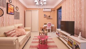 A modern living room with a sofa, TV, and a small table with a vase. - Shenzhen Maiya Apartment (Shenzhen)
