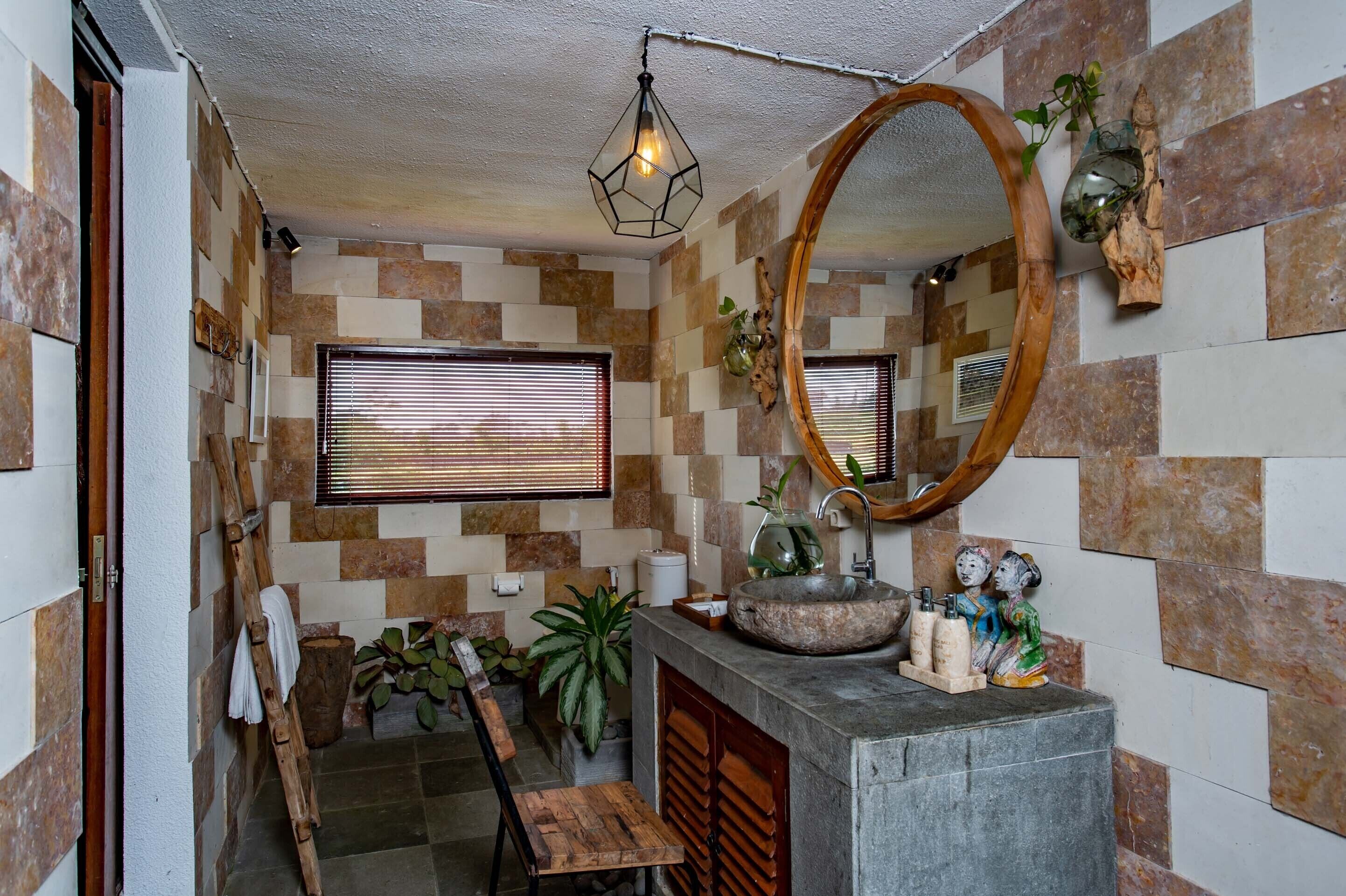 A bathroom with a checkered tile wall, a wooden vanity with a sink, a mirror, and a hanging light fixture.