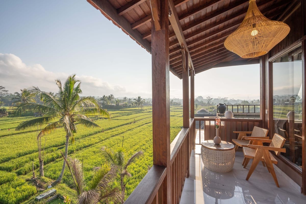 A balcony with a view of lush green fields and palm trees.