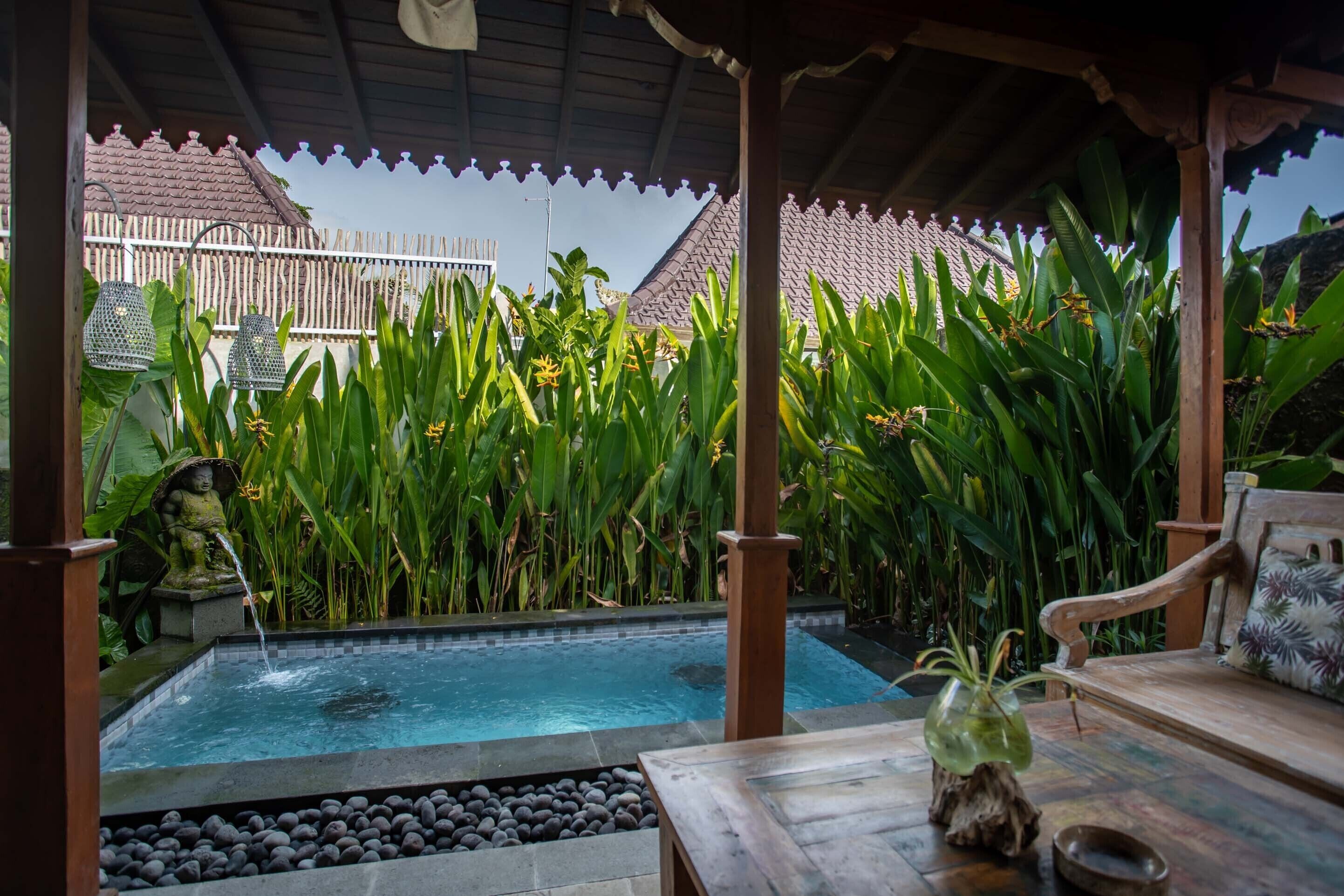 A pool area with a wooden bench and a statue.