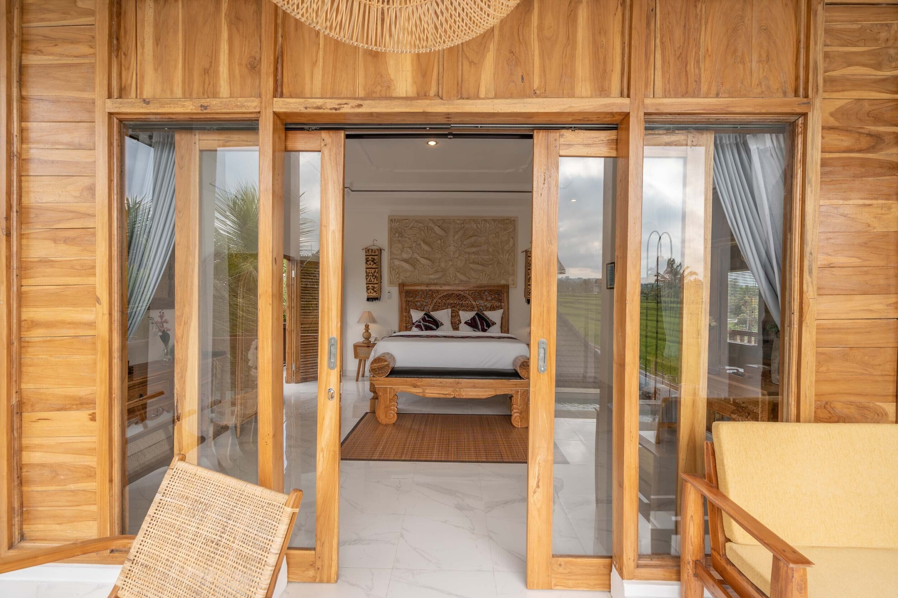 Una cabaña de madera con una cama grande, una silla de mimbre y vistas al exterior.