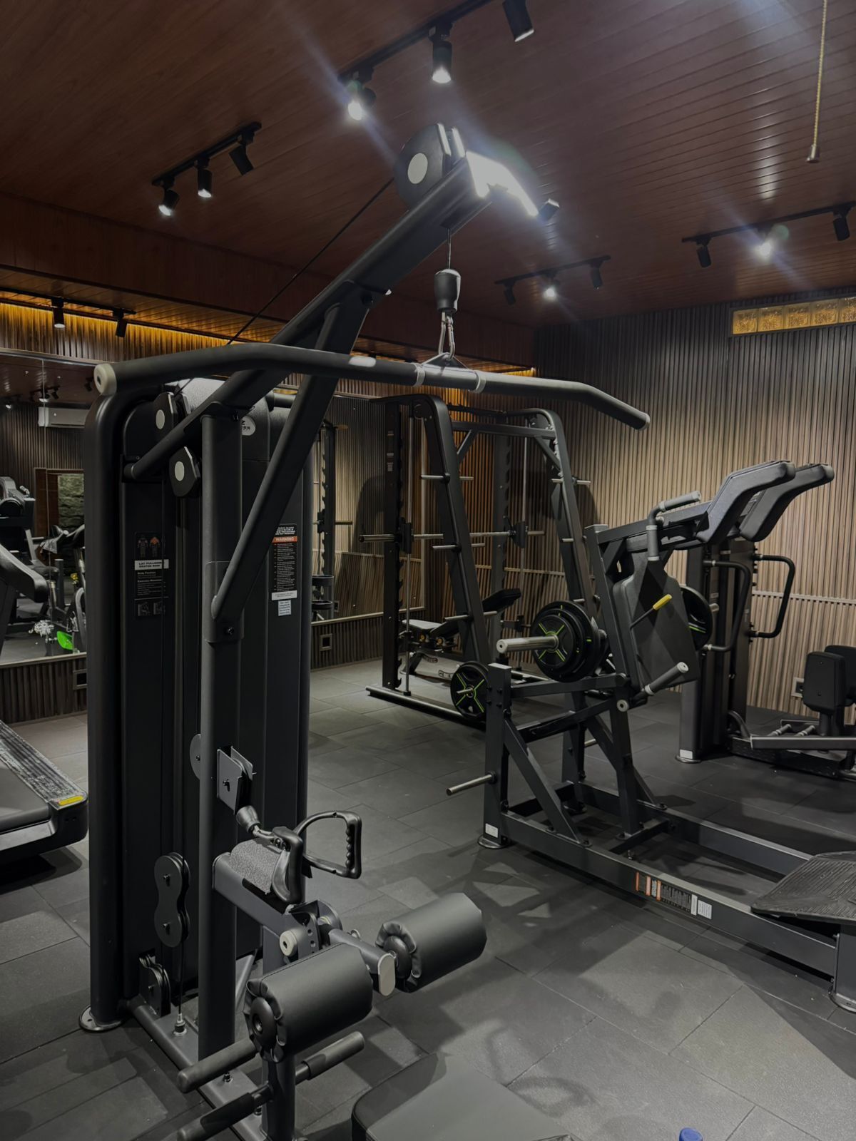 Een moderne sportschool met diverse fitnessapparaten, waaronder een squatraam en een bankdrukpers.