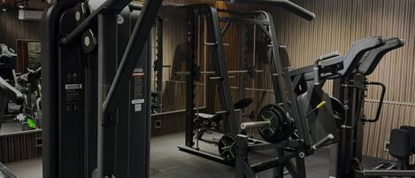 A modern gym with various exercise machines, including a squat rack and a bench press.