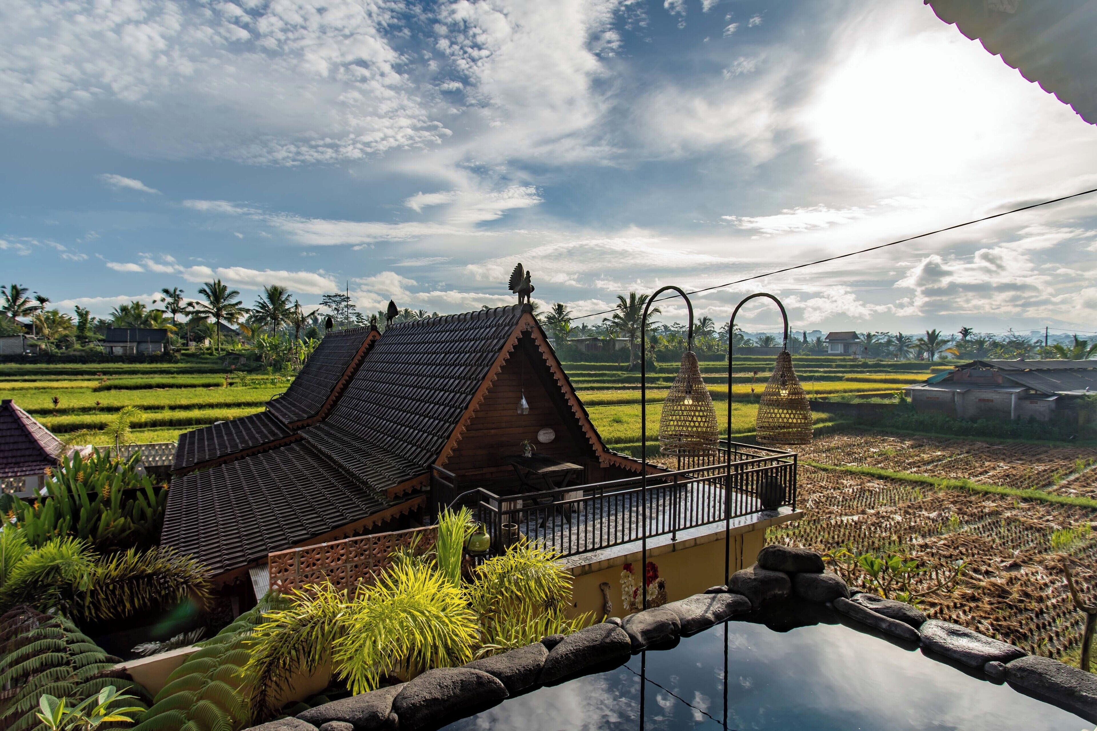 A traditional house with a tiled roof, a balcony, and a view of terraced rice fields.
