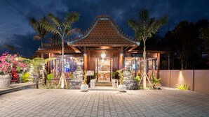 A traditional building with a tiled roof, a central entrance, and a paved courtyard.
