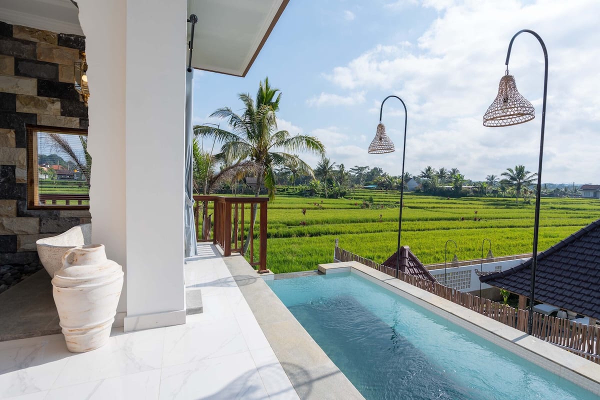 A pool area with a view of green fields and palm trees.