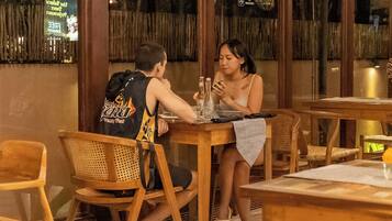 A restaurant with wooden furniture, a table with a bottle and glasses, and a person sitting at the table.
