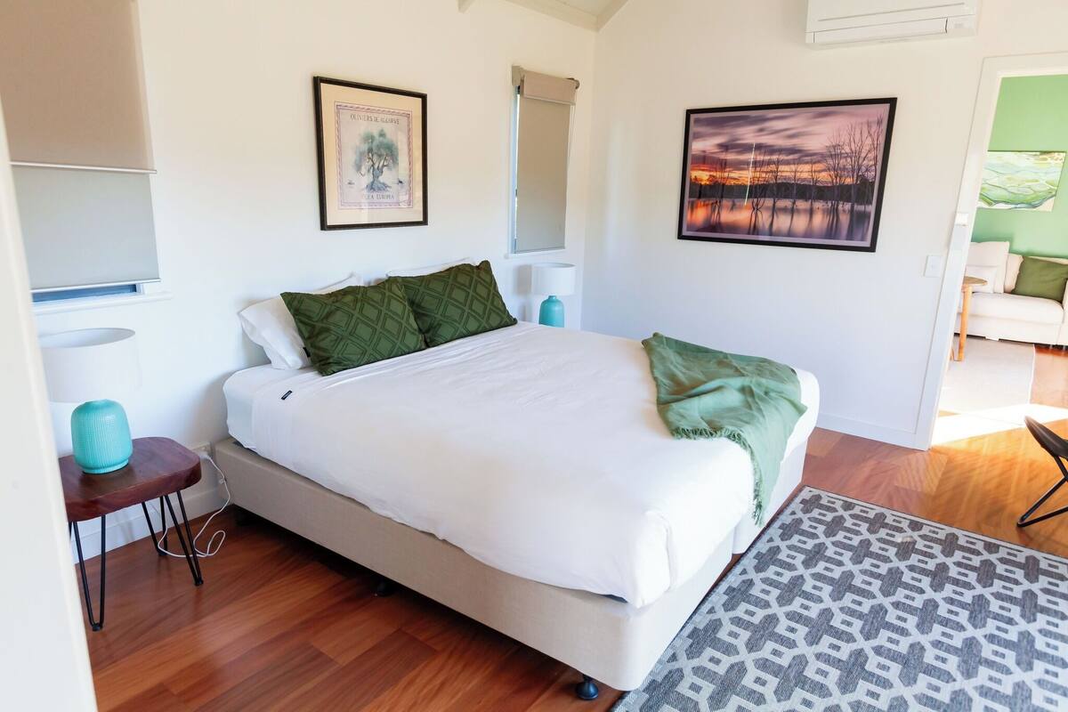 A bedroom with a bed, a bedside table, a lamp, and a picture on the wall.