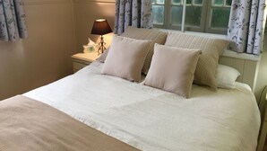 A neatly made bed with a textured bedspread, two pillows, and a bedside lamp on a nightstand. - Boonah Cottage (Boonah)
