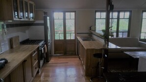 A kitchen with wooden cabinets, a stove, and a large window. - Boonah Cottage (Boonah)