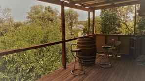 A wooden deck with a rustic barrel, two bar stools, and a wicker chair. - Boonah Cottage (Boonah)