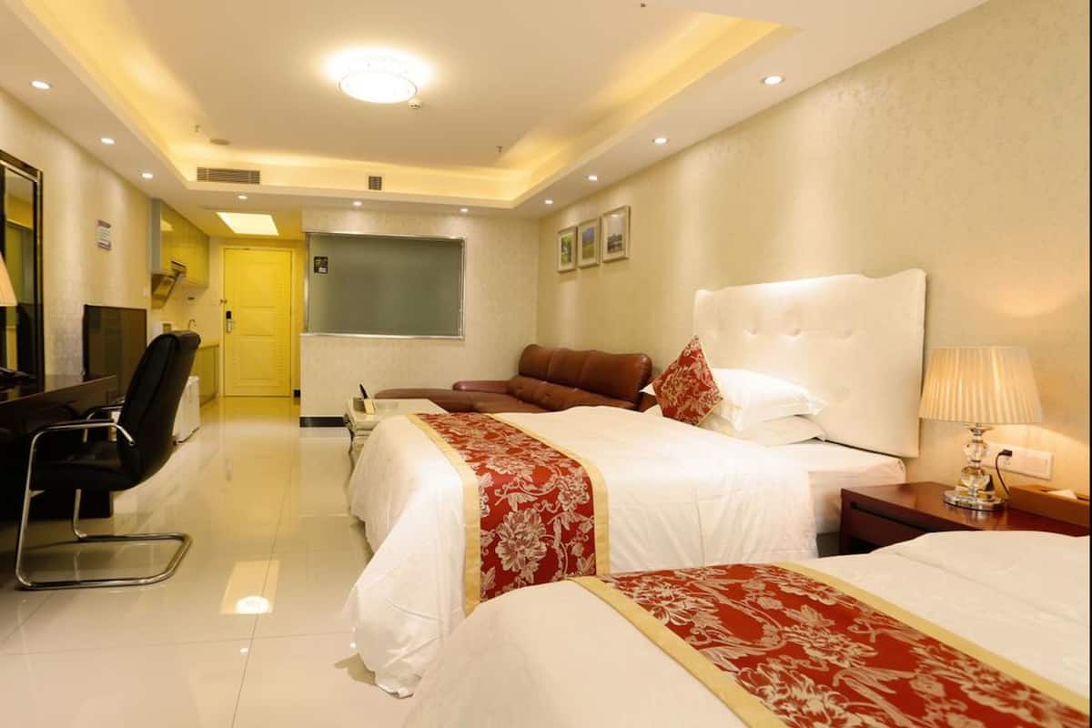 A hotel room with a large bed, a smaller bed, a desk with a chair, a TV, and a window.