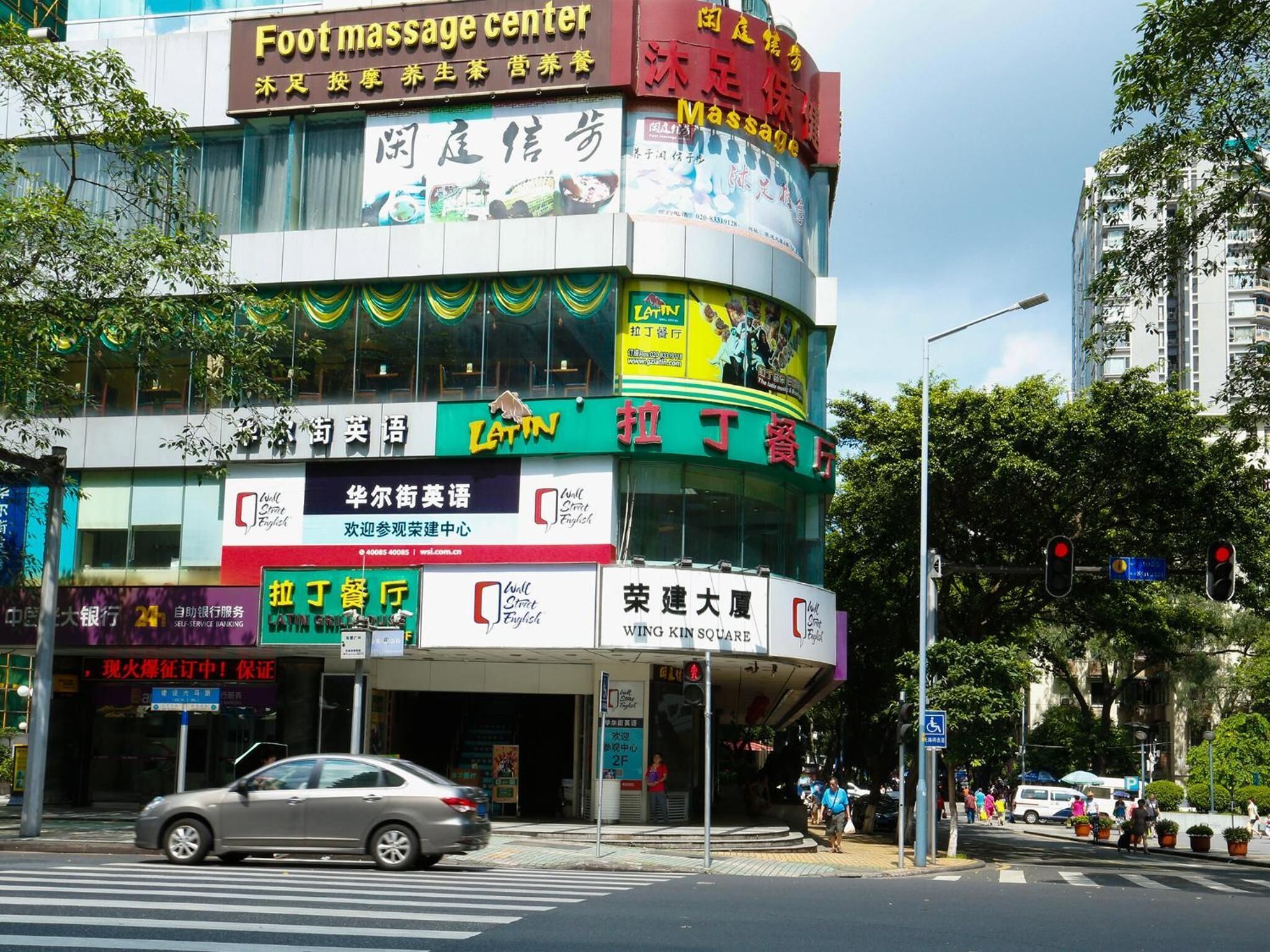Un edificio de varios pisos con locales comerciales, incluyendo un centro de masajes podales, un restaurante latino y una sucursal bancaria.