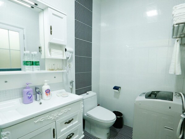 Un baño con lavamanos blanco, un espejo, inodoro y zona de ducha.